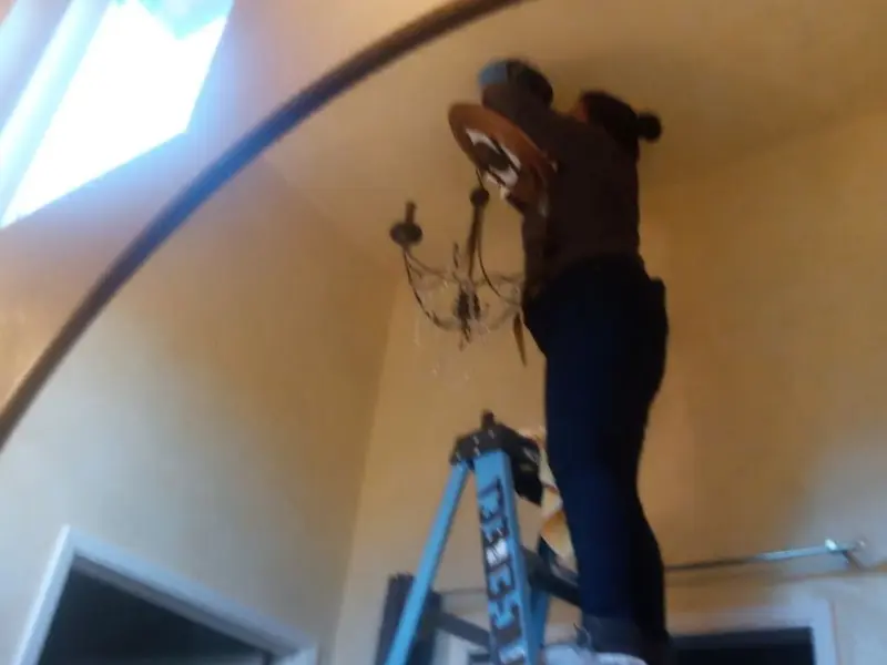 Electrician installing a chandelier in a Flowood residence